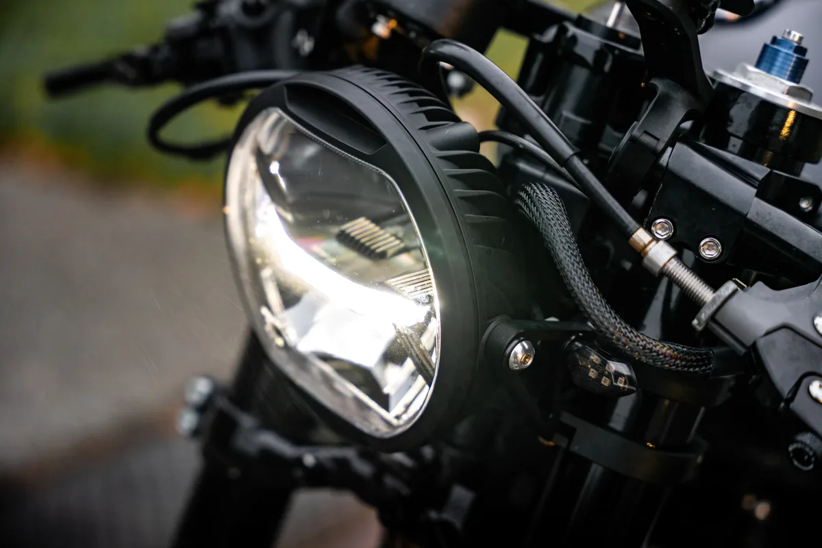 Gros plan sur le phare et le guidon d’une moto rétro noire.