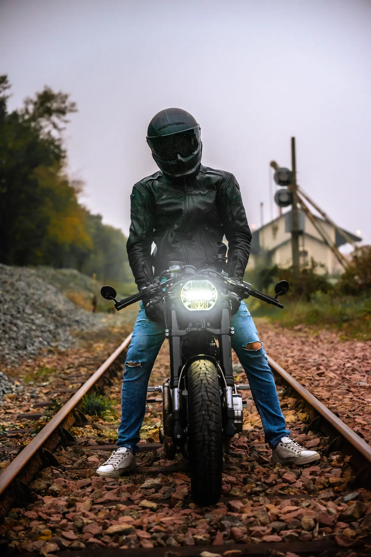 Un motard roule vers l’objectif sur une voie ferrée en automne.