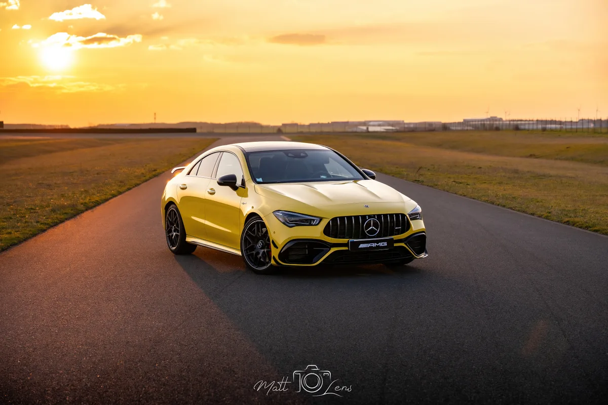 Coupé sportif jaune photographié sur circuit au coucher du soleil.