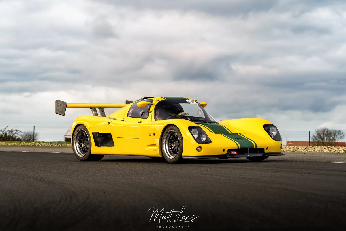 Voiture de course jaune photographiée de profil sur la piste.