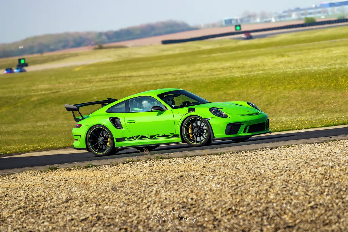 Porsche verte en pleine accélération sur un circuit automobile.