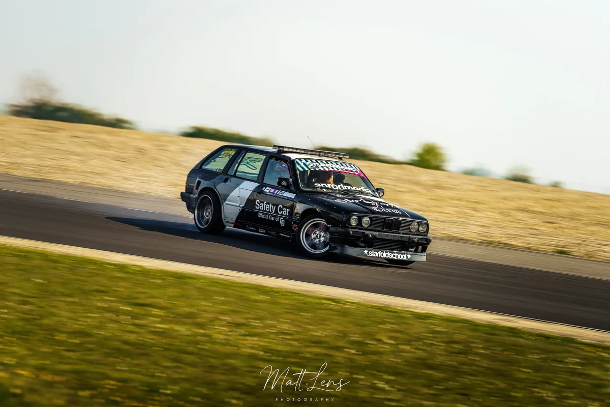 Une voiture compacte noire passe un virage sur le circuit.