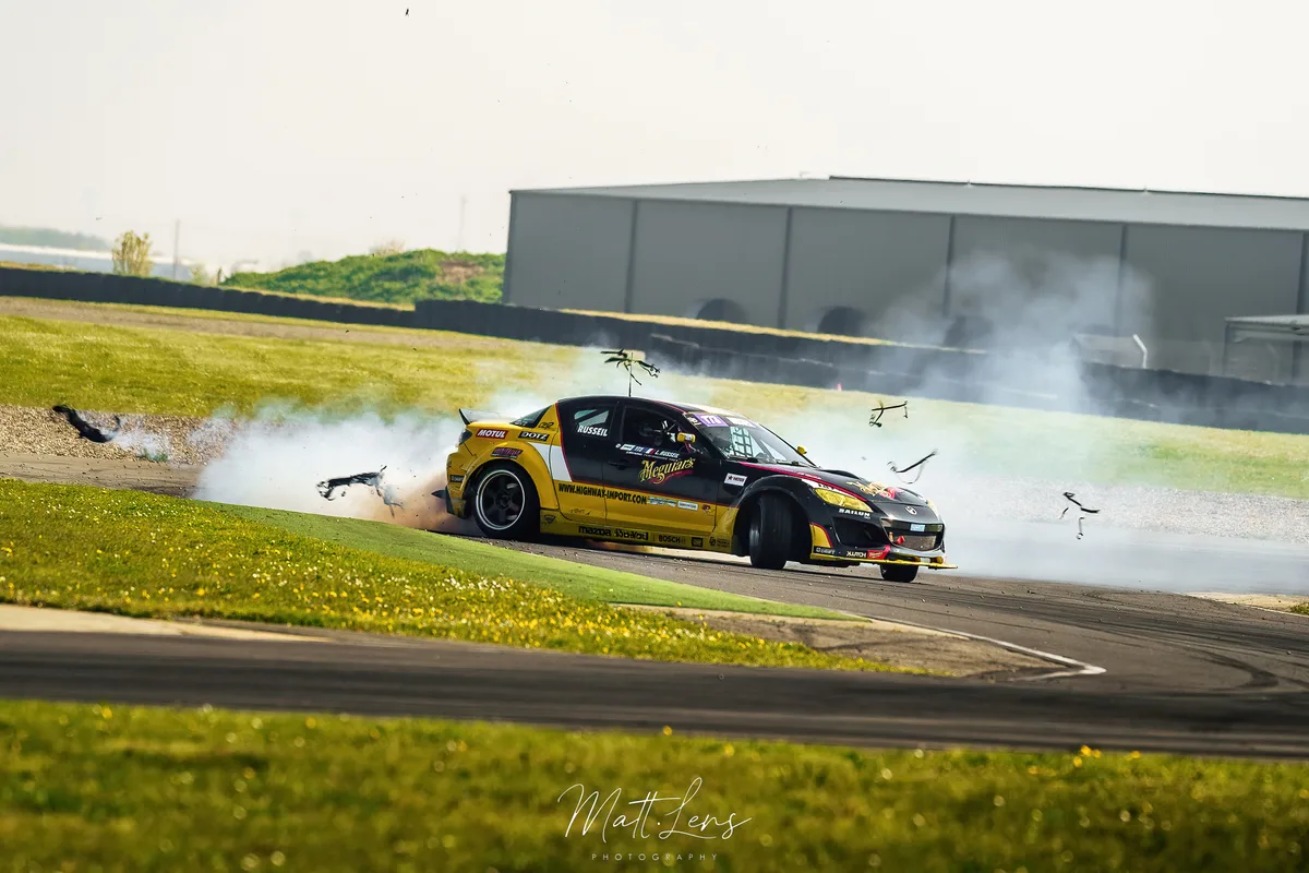 Une voiture noire en démonstration de drift fait fumer ses pneus.