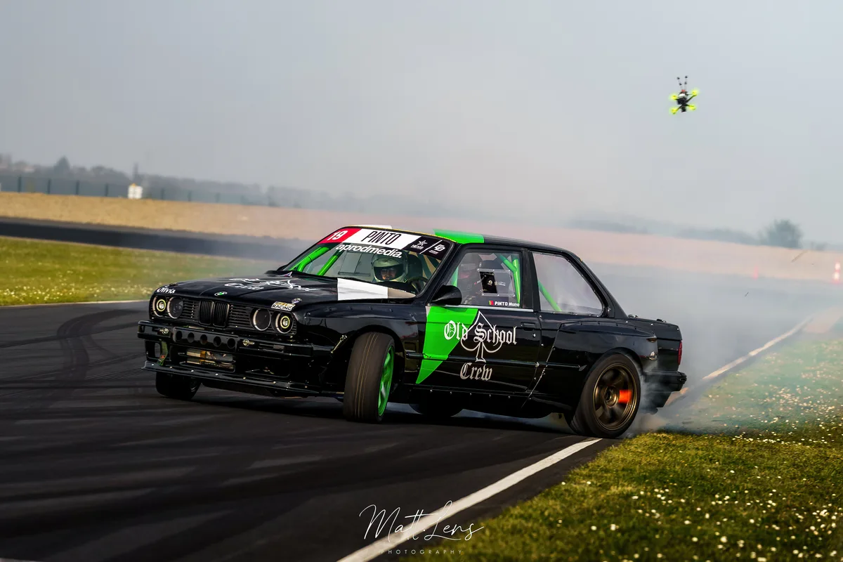 La voiture noire et verte dérive sur la piste devant les spectateurs.