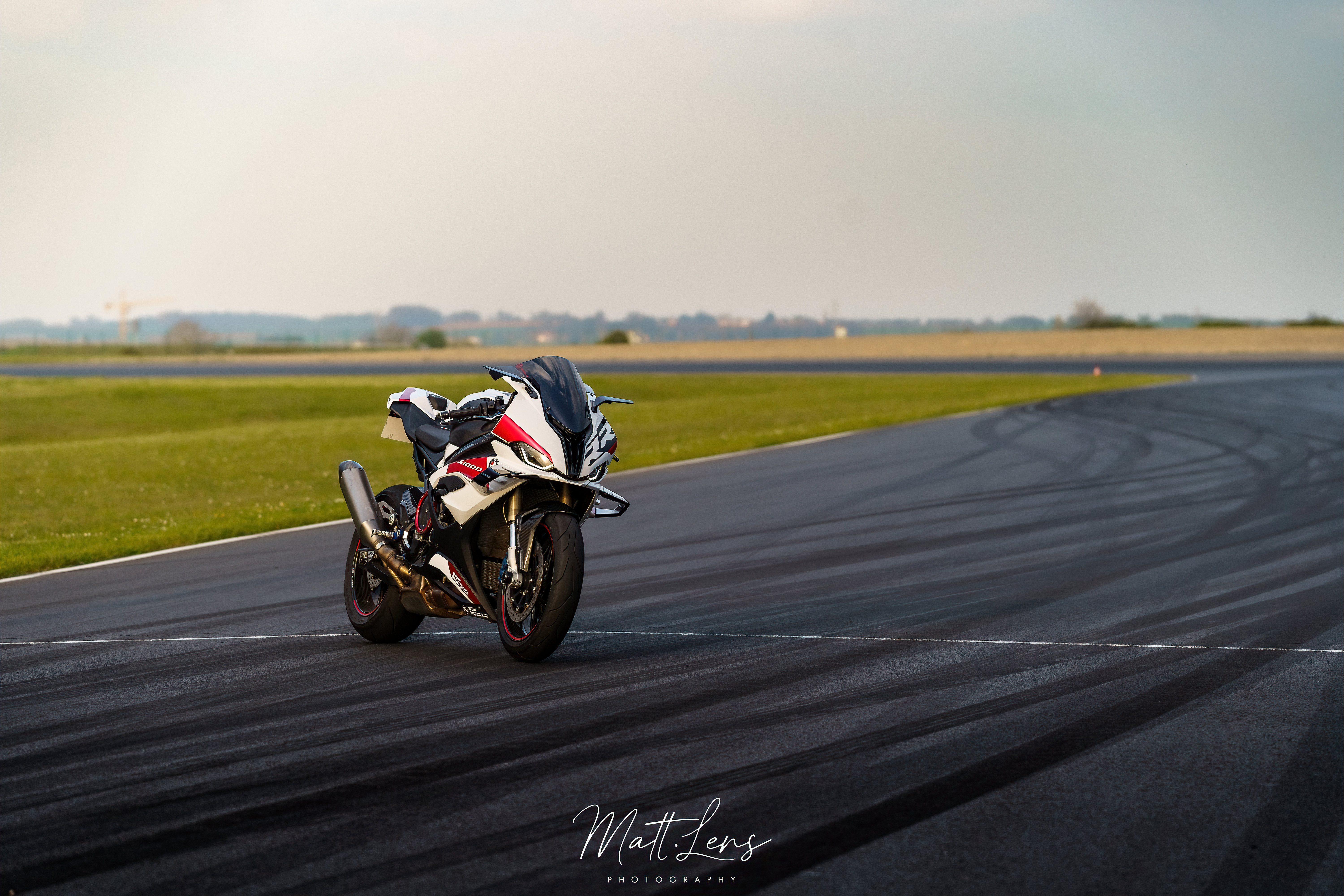Un motard prend un virage sur circuit sous un ciel couvert.