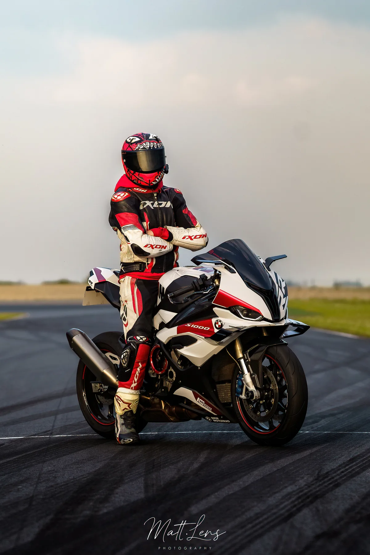 Un pilote en casque rouge roule sur une moto sportive sur circuit.