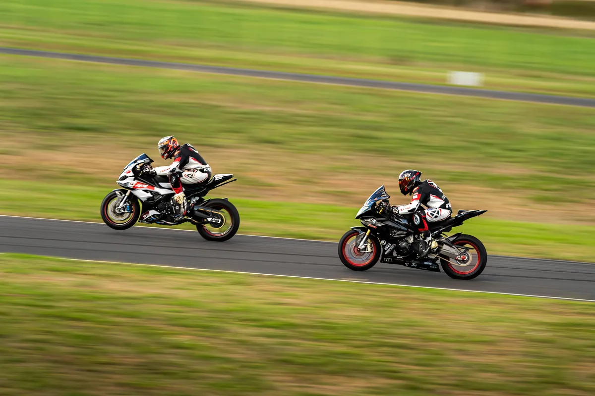 Deux motos se poursuivent sur le circuit dans un décor de fin d’été.
