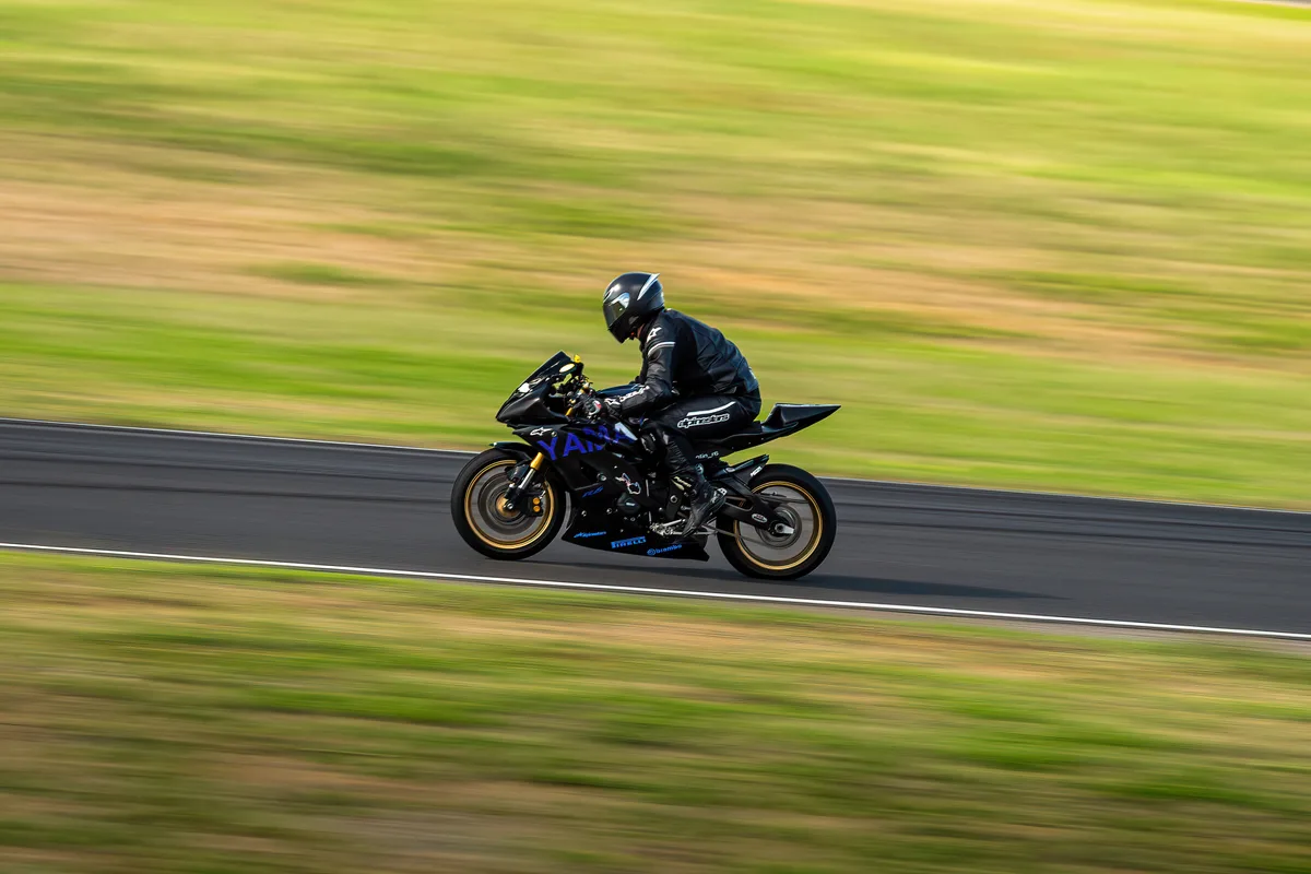 Un motard file sur la piste, avec le décor flouté en arrière-plan.