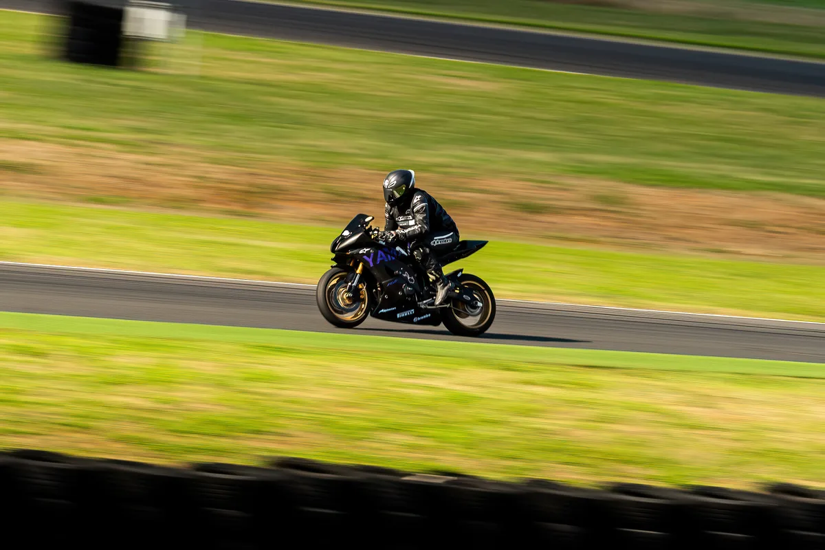 Un motard traverse la piste, photographié en filé latéral.