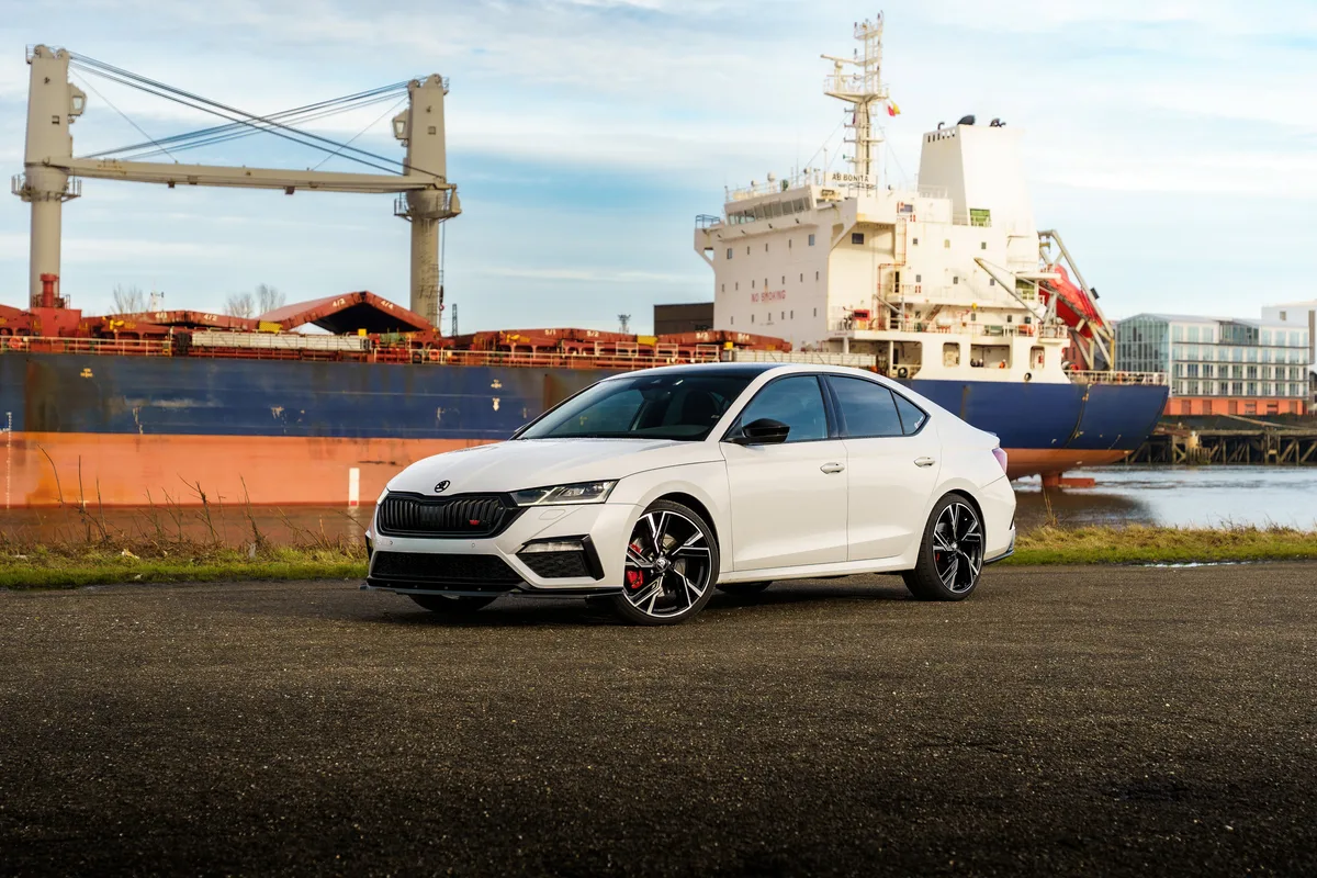 Skoda blanche photographiée près d’un port et d’un cargo.