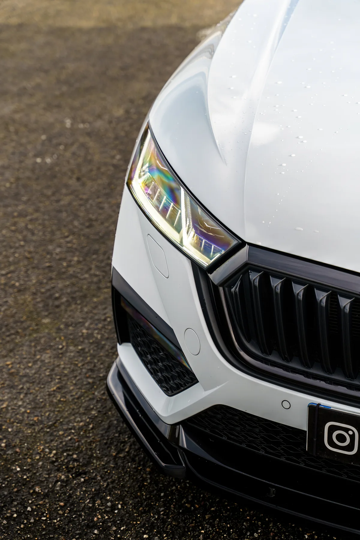 Détail de la calandre et du phare de la Skoda blanche.