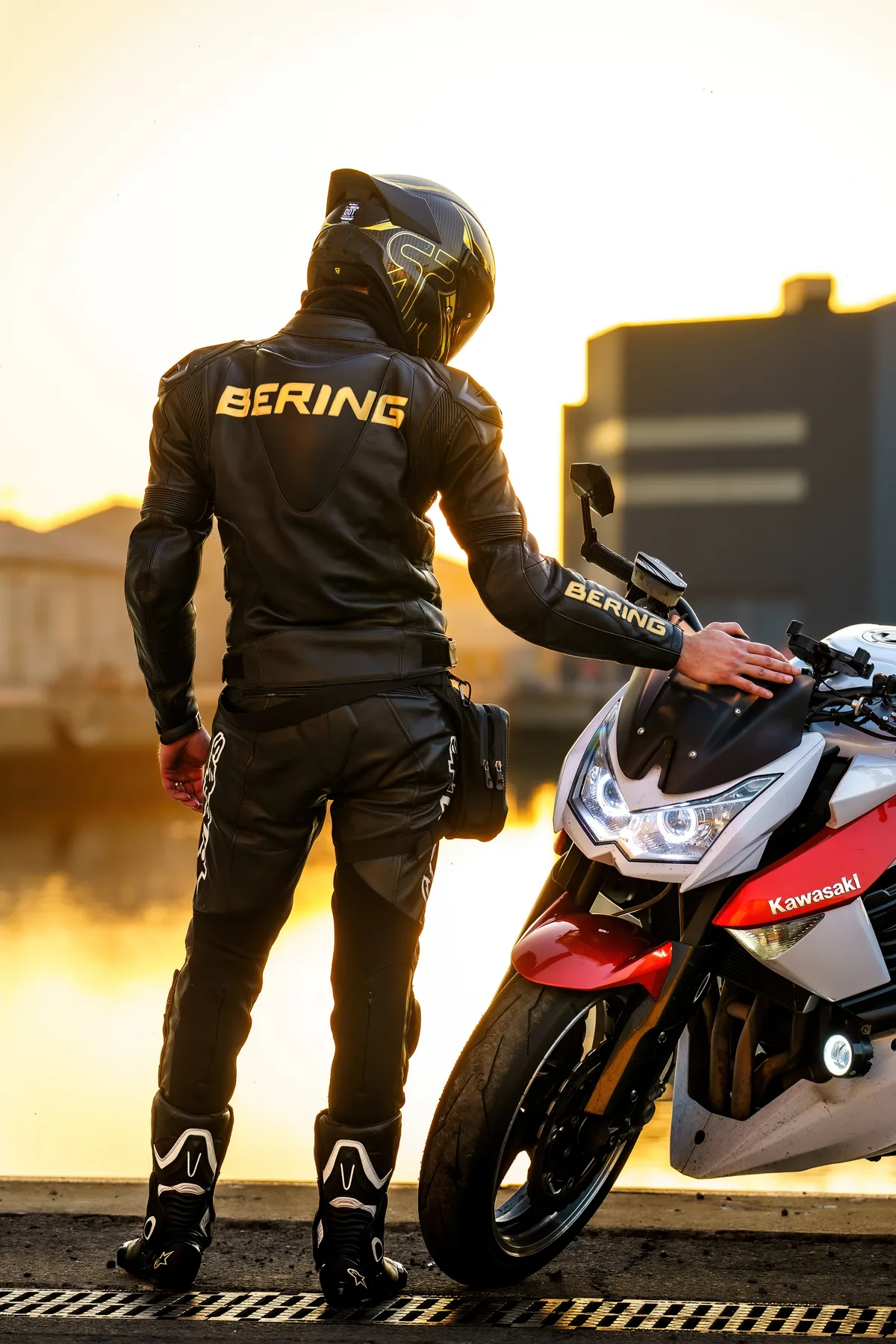Un motard en casque rouge se tient près de sa moto après la séance.