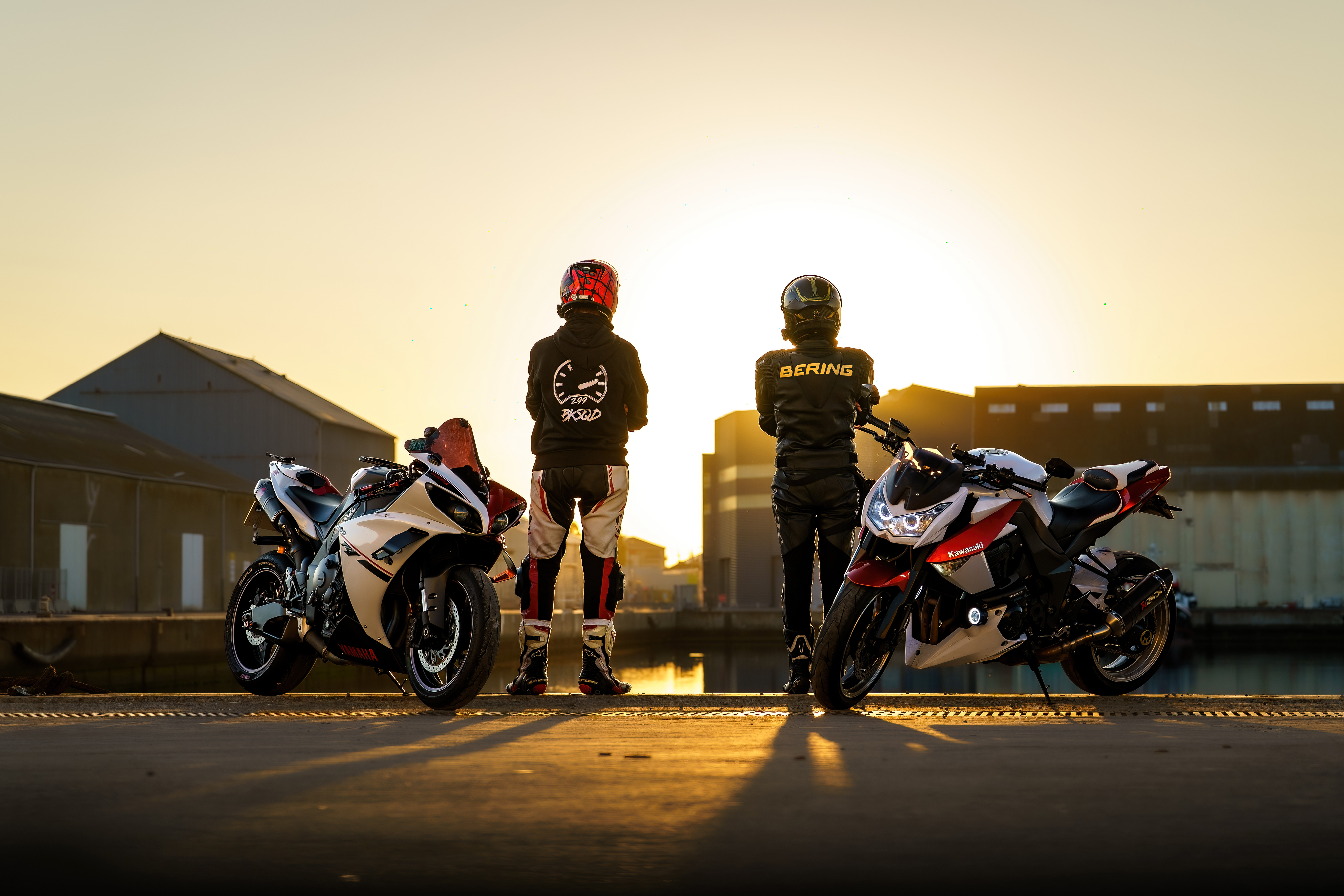 Deux motards posent avec leurs motos dans la lumière du soir.