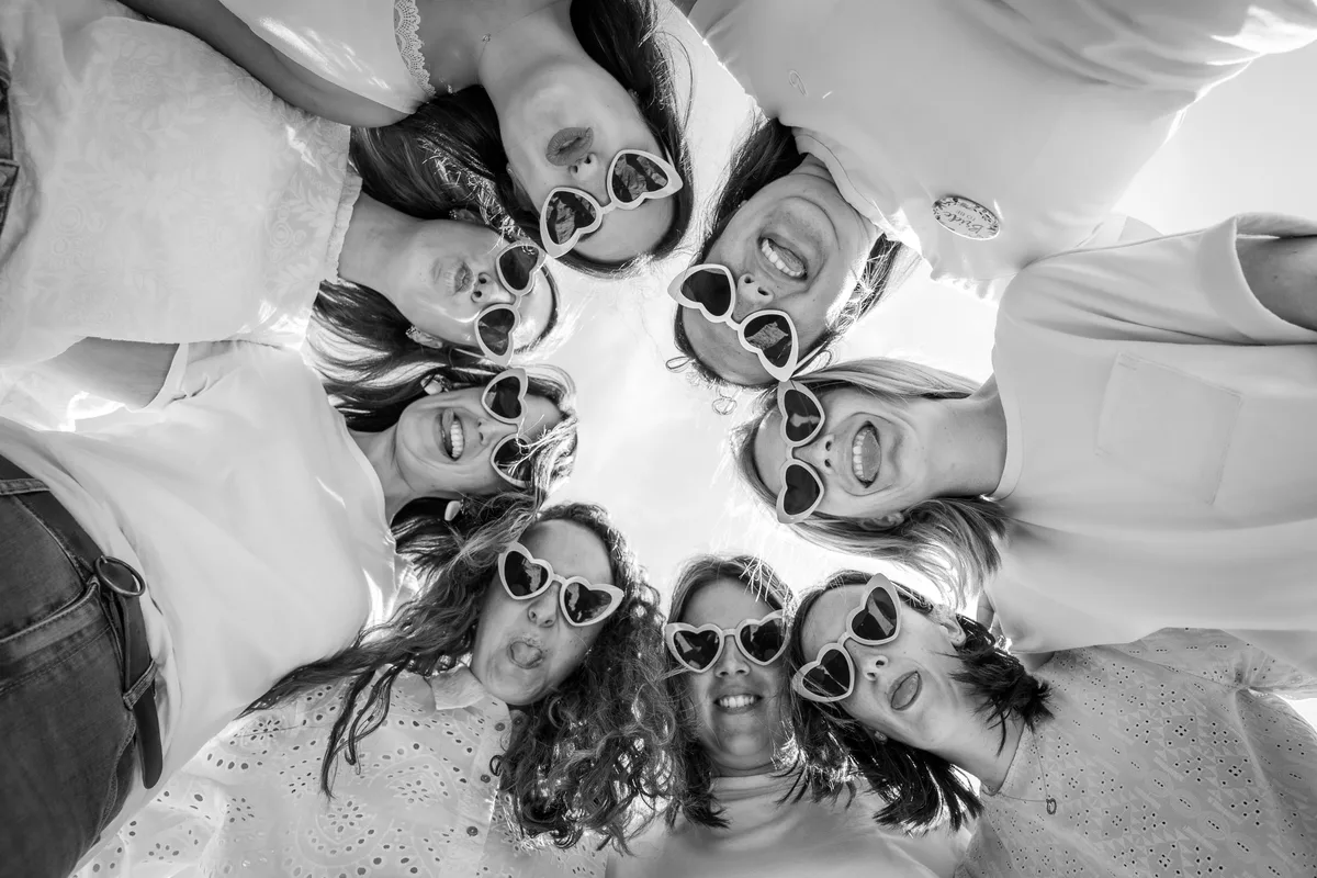 Portrait de groupe vu du dessus, les amies réunies en cercle sur le sable.