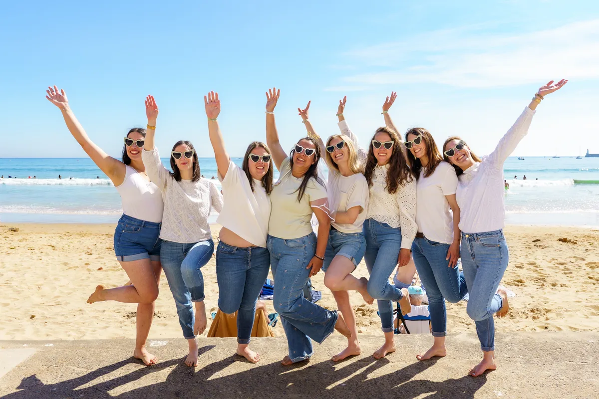 Les amies lèvent les bras ensemble sur la plage au coucher du soleil.