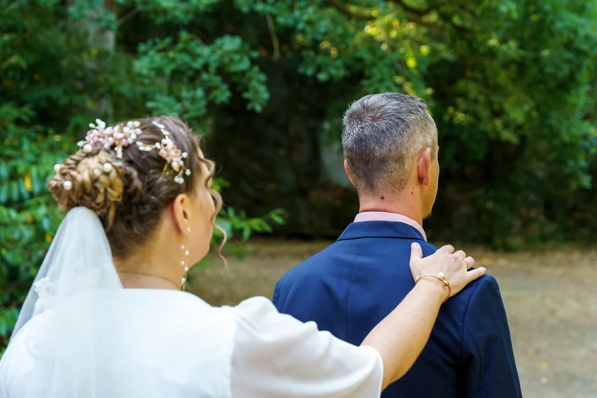 Le marié enlace la mariée dans le jardin, photographiés de dos.