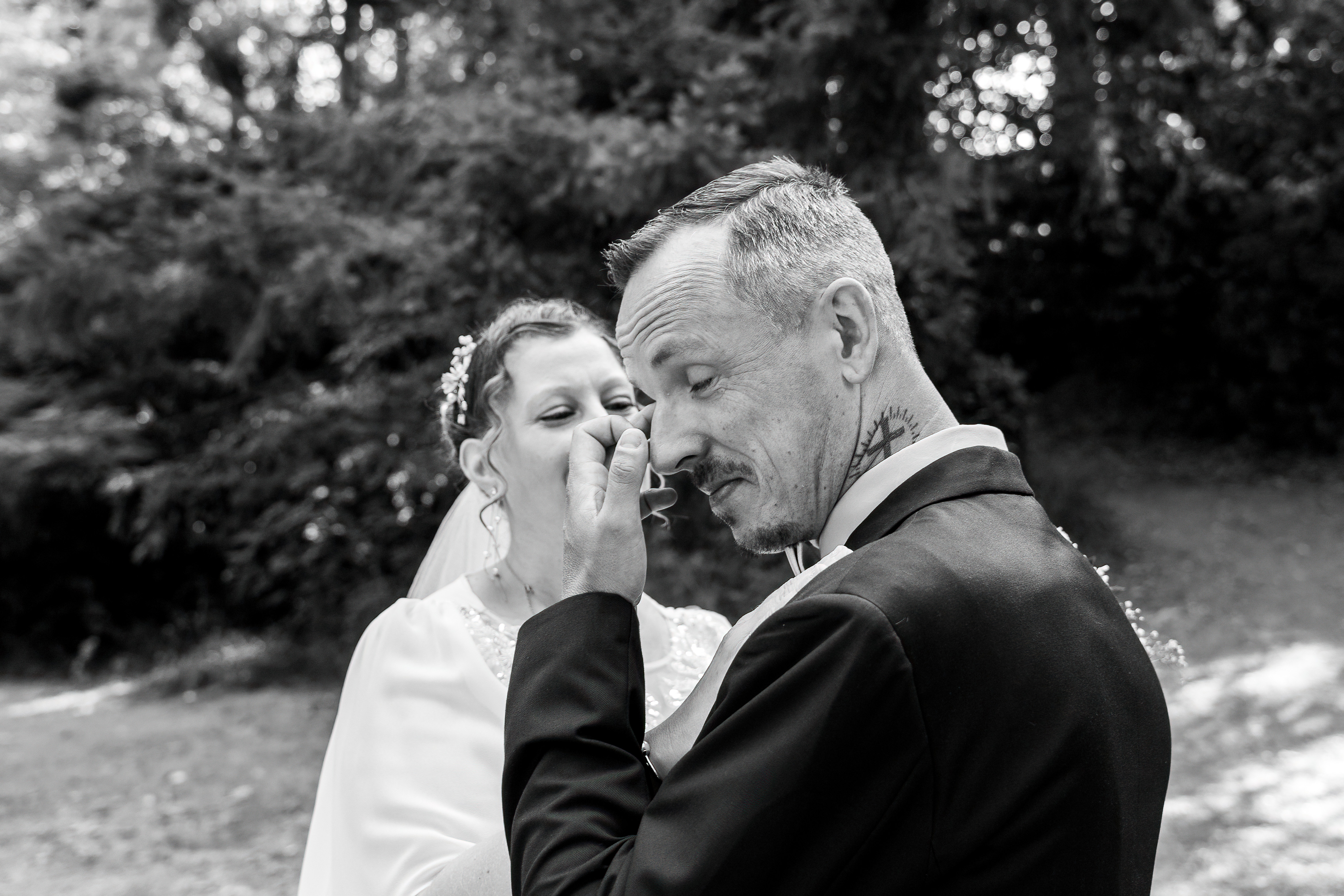 Baiser des mariés en noir et blanc, capté sur le vif dans le jardin.