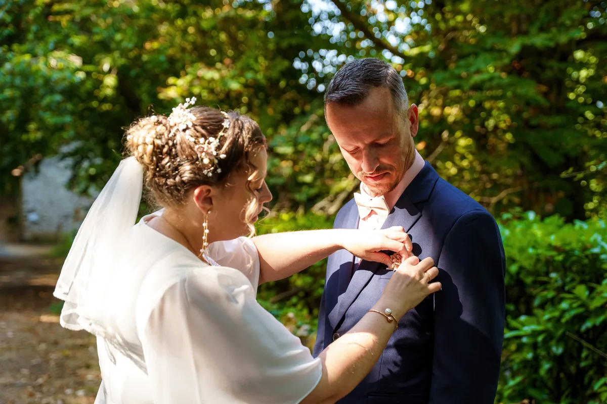 La mariée ajuste le revers du costume du marié avant la cérémonie.