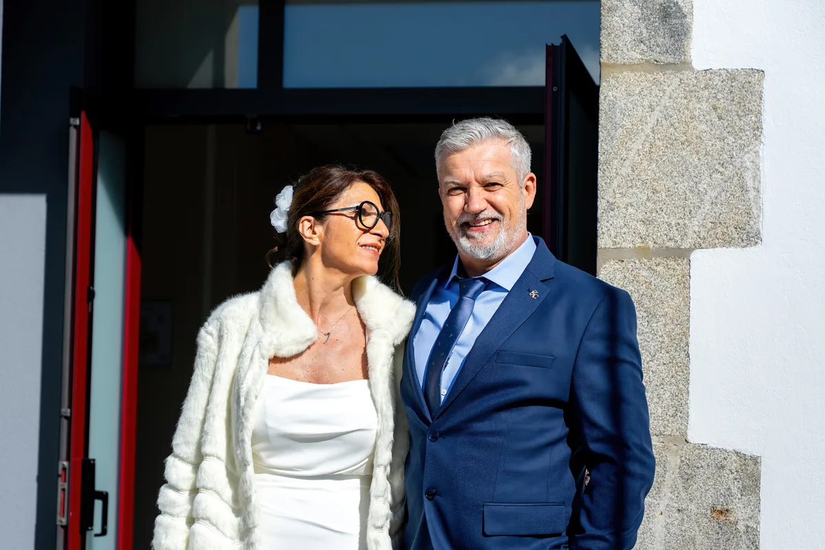 Les mariés posent ensemble à l’entrée de la salle de réception.