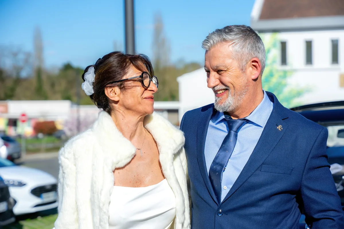 Portrait des mariés côte à côte devant la salle de réception.