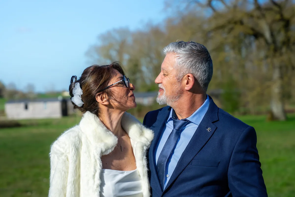 Les mariés se regardent tendrement dans le jardin.