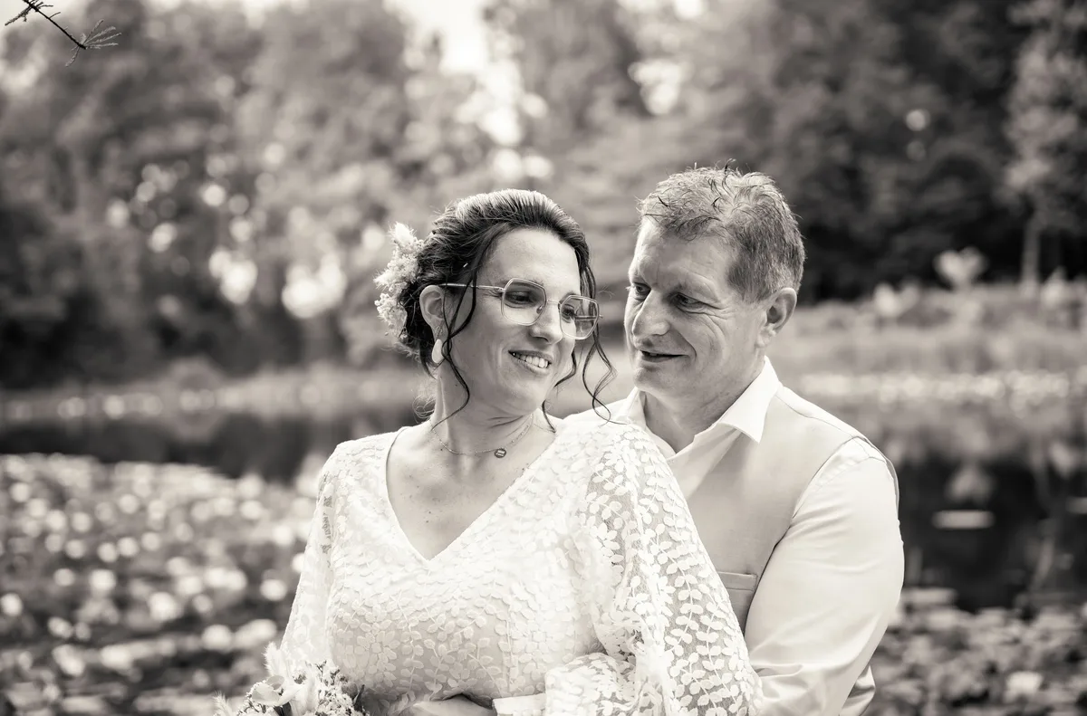 Portrait en noir et blanc des mariés enlacés dans le jardin.