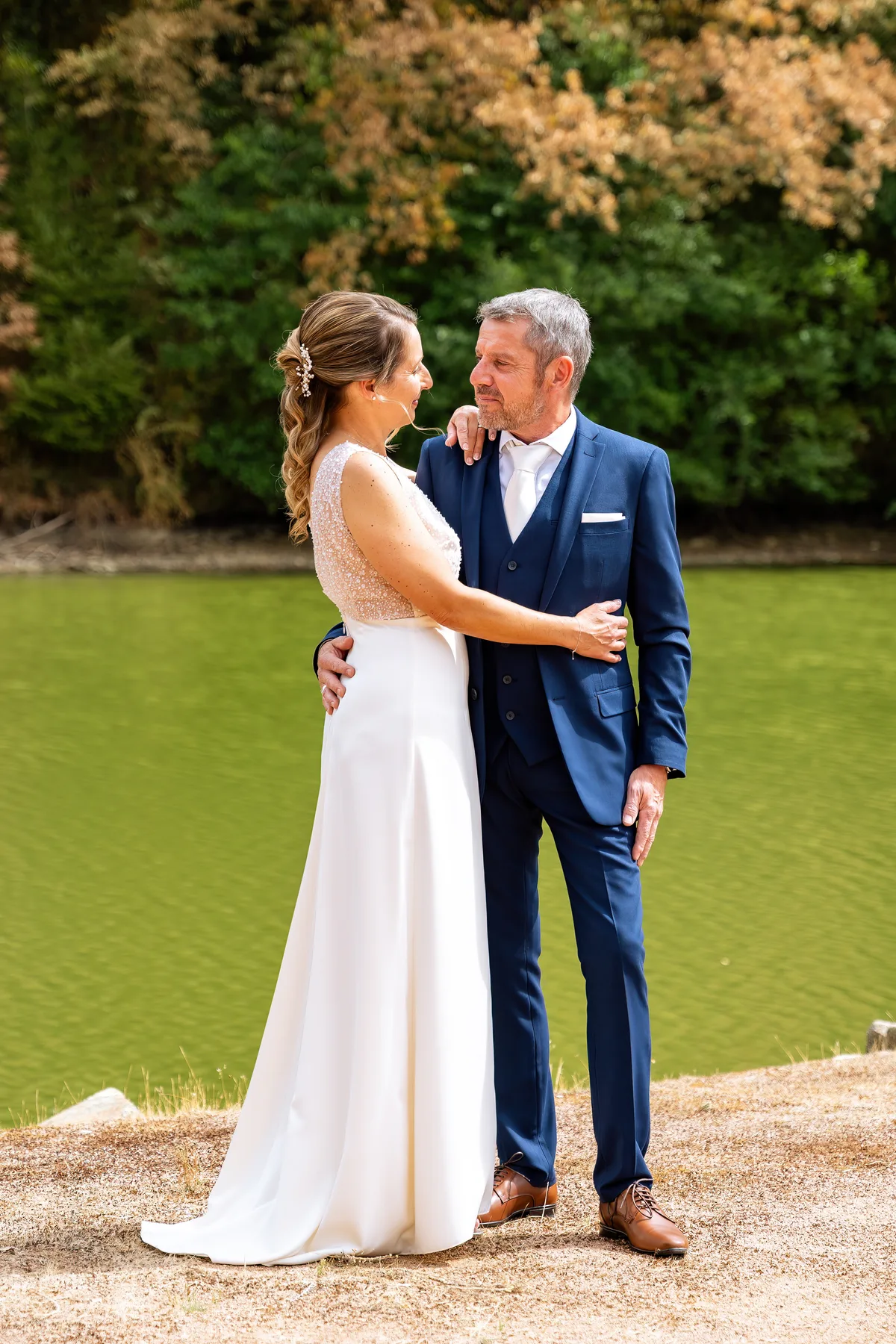 Les mariés se font face dans un jardin, photographiés en pied.