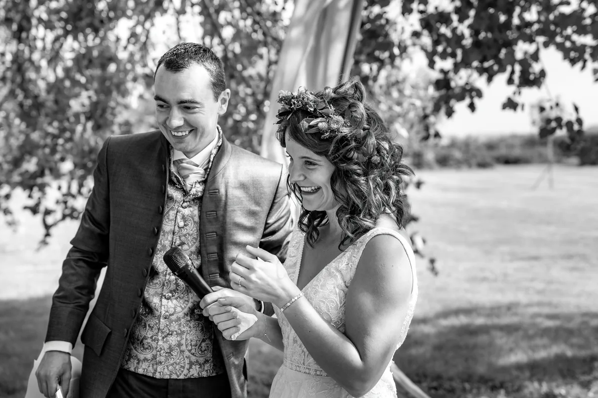 Les mariés partagent un sourire en noir et blanc dans le jardin.