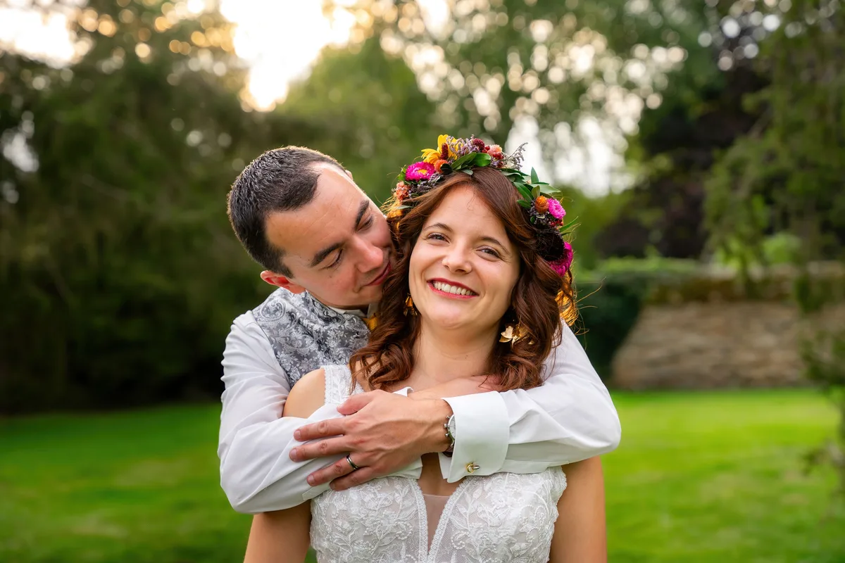 Le marié enlace la mariée dans le jardin après leur mariage.
