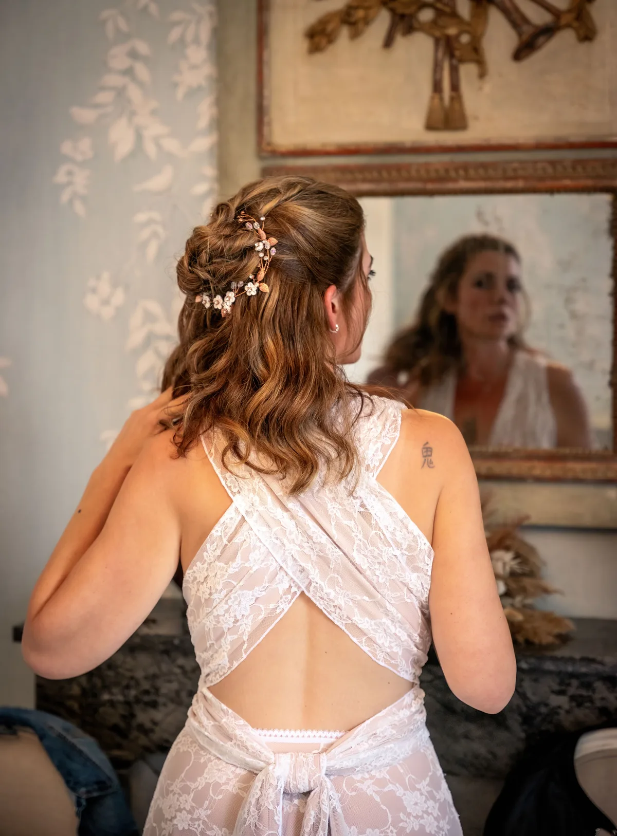 La mariée ajuste sa robe devant le miroir avant la cérémonie.