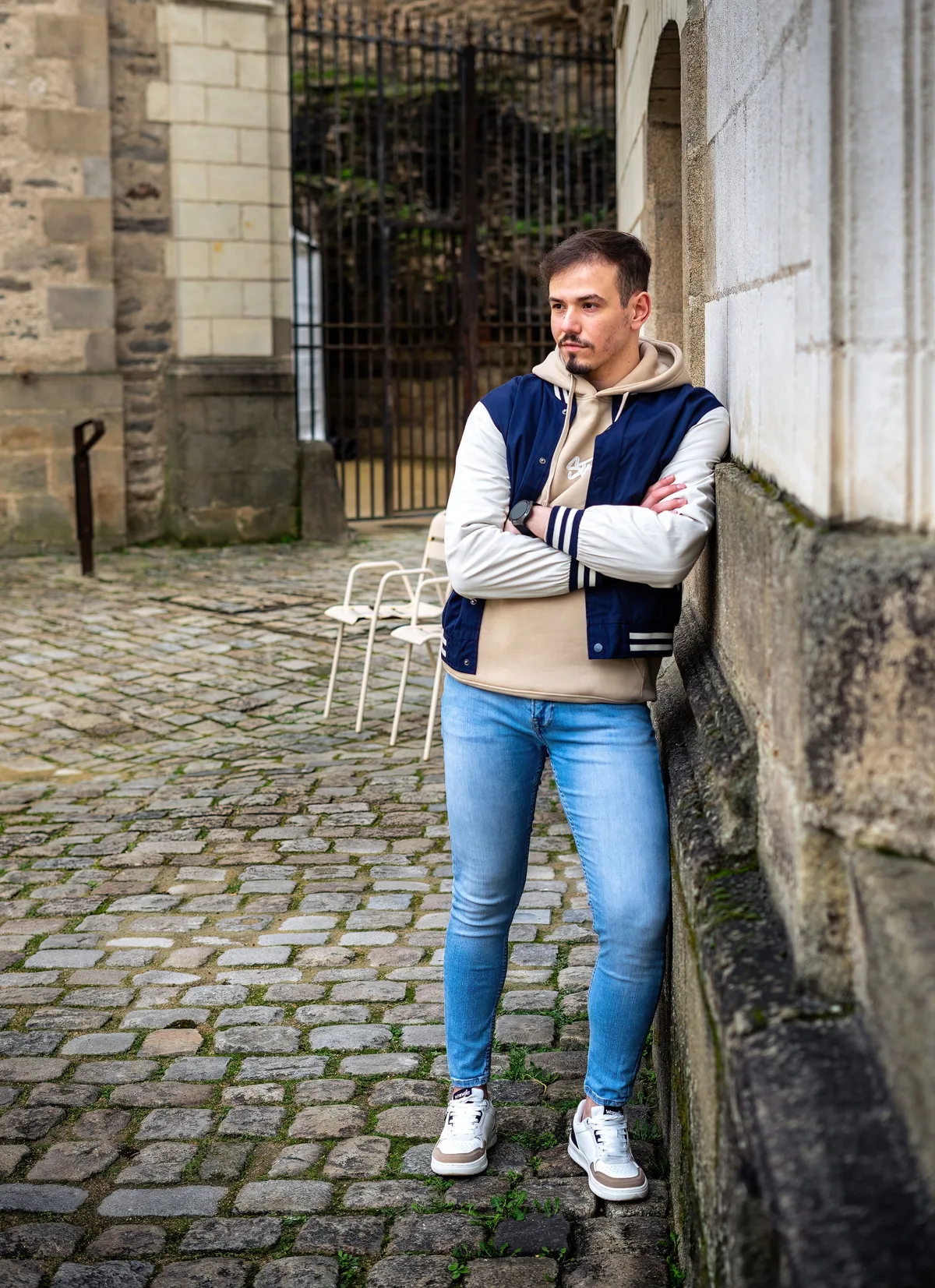 Portrait de Mohamed assis devant un mur de pierre en ville.