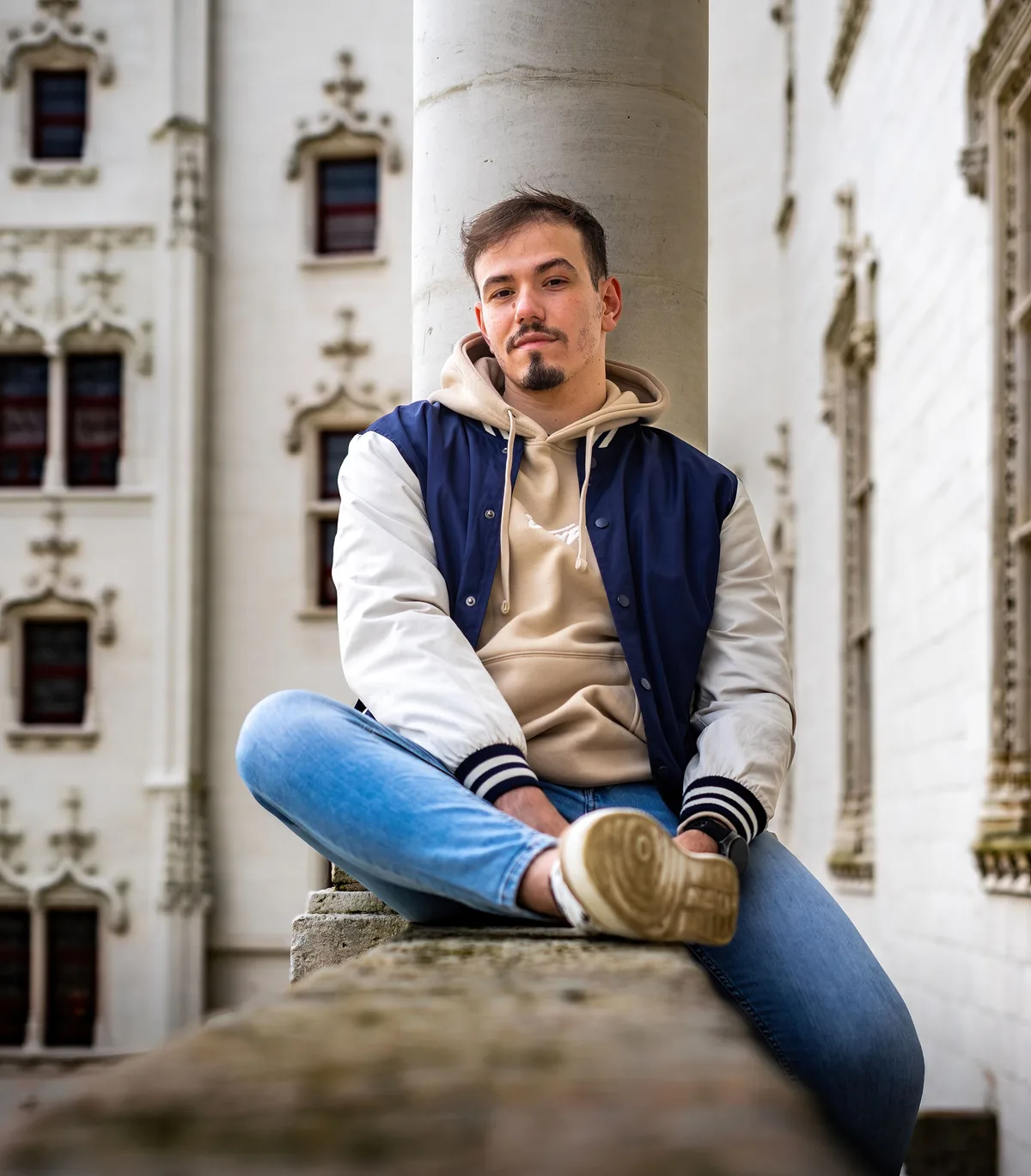 Portrait de Mohamed assis sur les marches d’un bâtiment ancien.