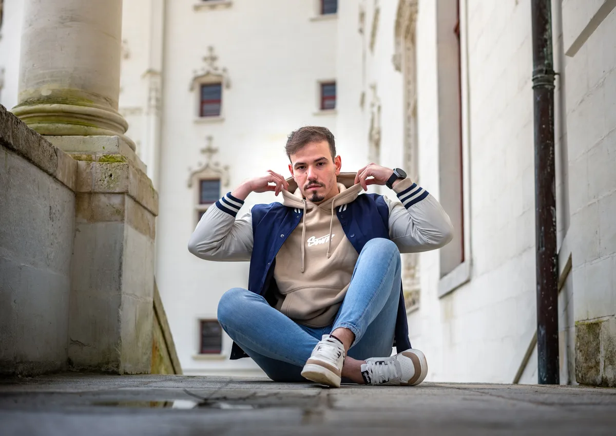 Mohamed ajuste le col de sa veste dans un escalier en pierre.