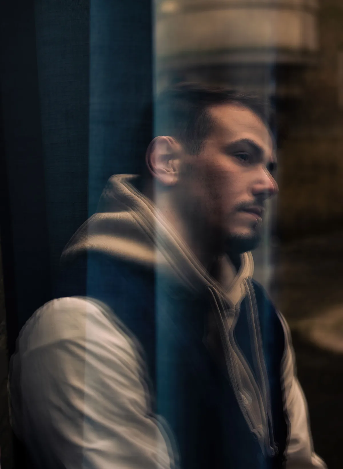 Portrait de Mohamed derrière une vitre, avec un effet de mouvement.