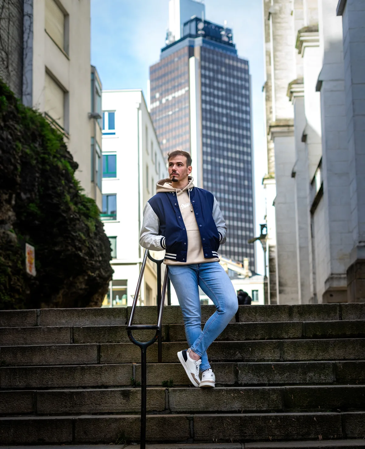 Mohamed pose dans un escalier au cœur d’une rue urbaine.