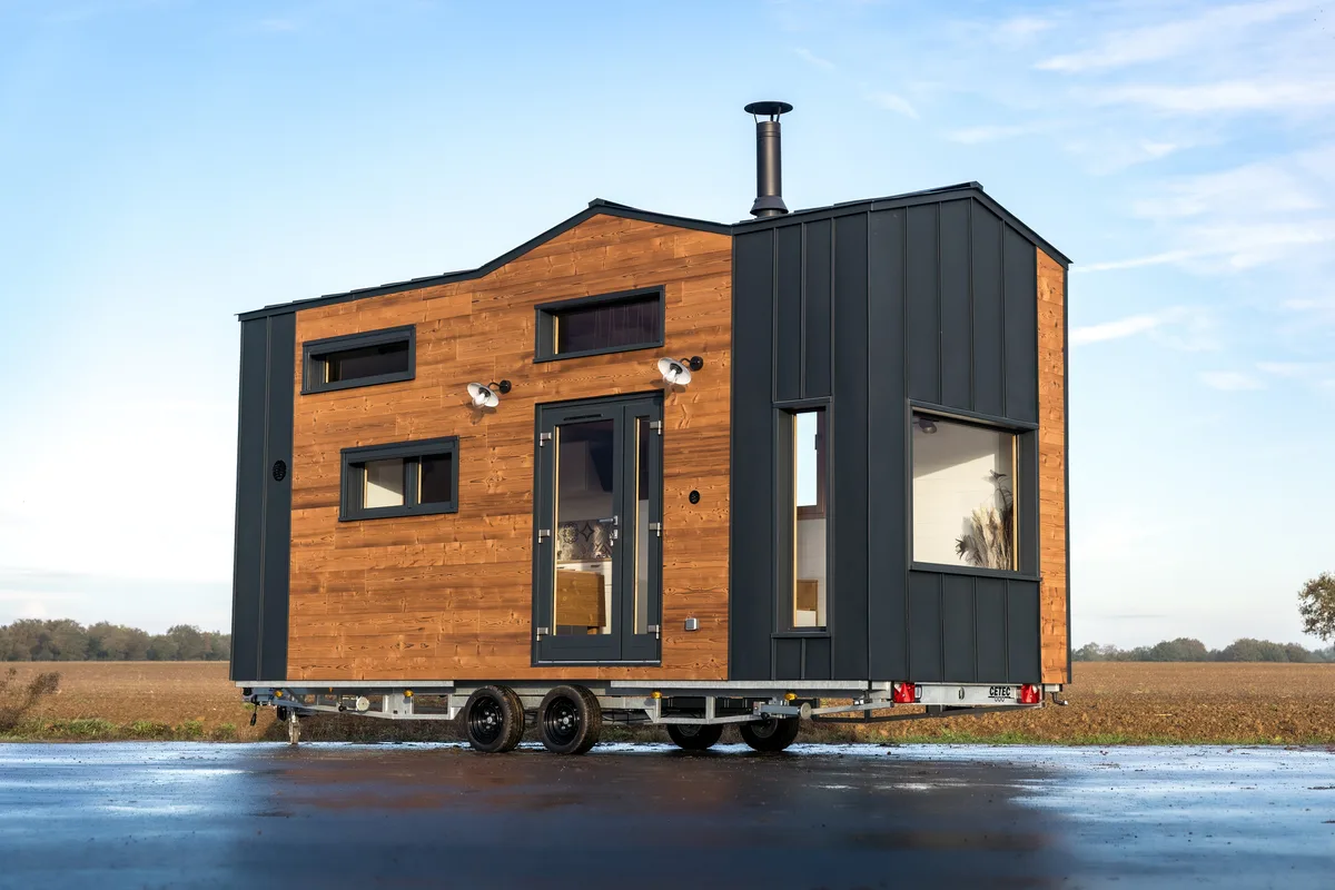 Tiny house en bois photographiée de l’extérieur au bord de l’eau.